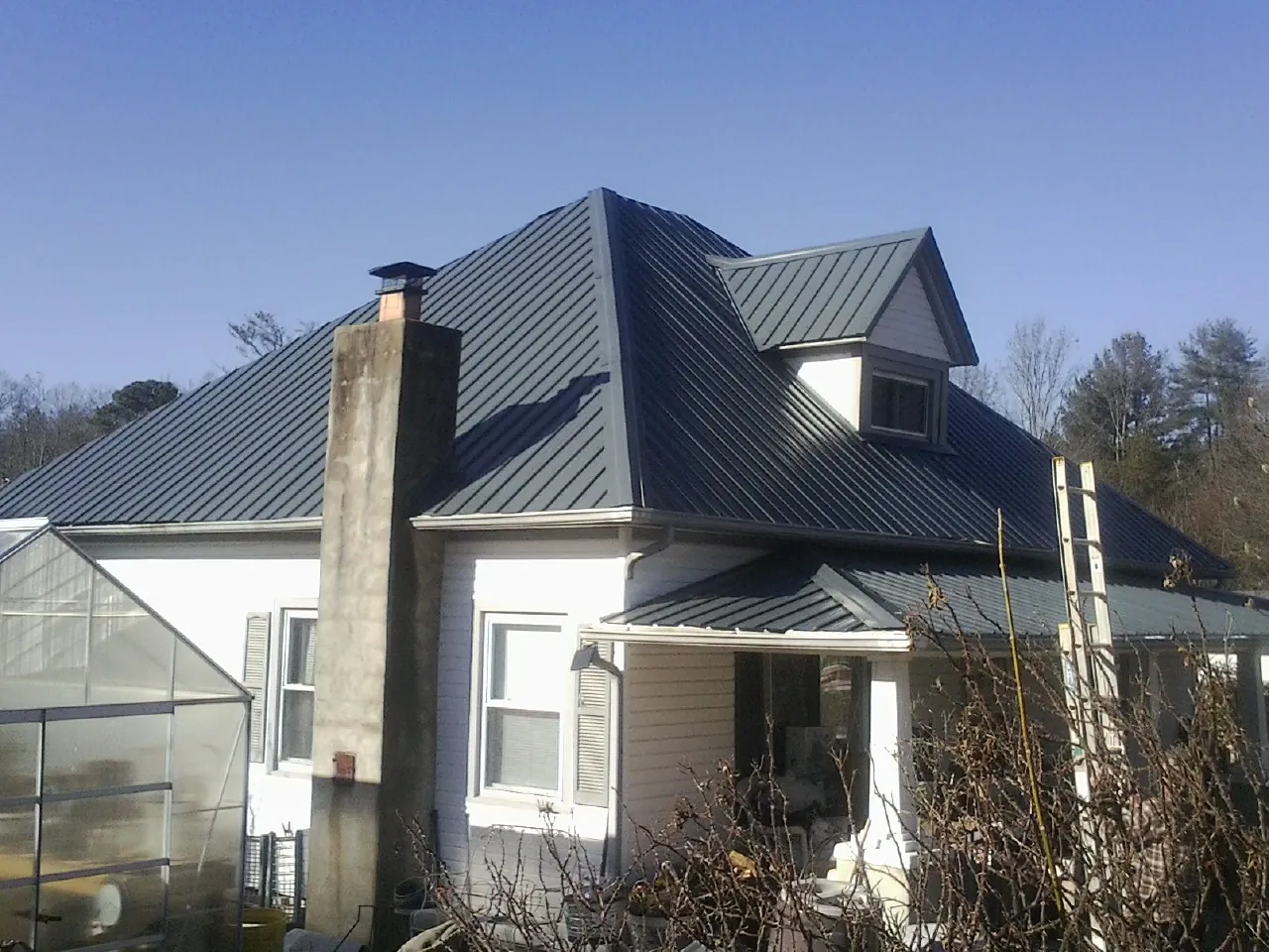 Dark blue standing seam metal roof on a white farmhouse with dormer — Slate & Tile Roof Repair by Roofing Brothers in Harsens Island
