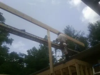 Carpenter setting a ridge beam over a new addition frame — Ice Dam Removal by Roofing Brothers in Harsens Island
