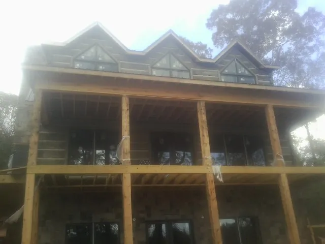 Dormers and porch framing on a large log home under construction — Roof Coating work by our crew in Harsens Island