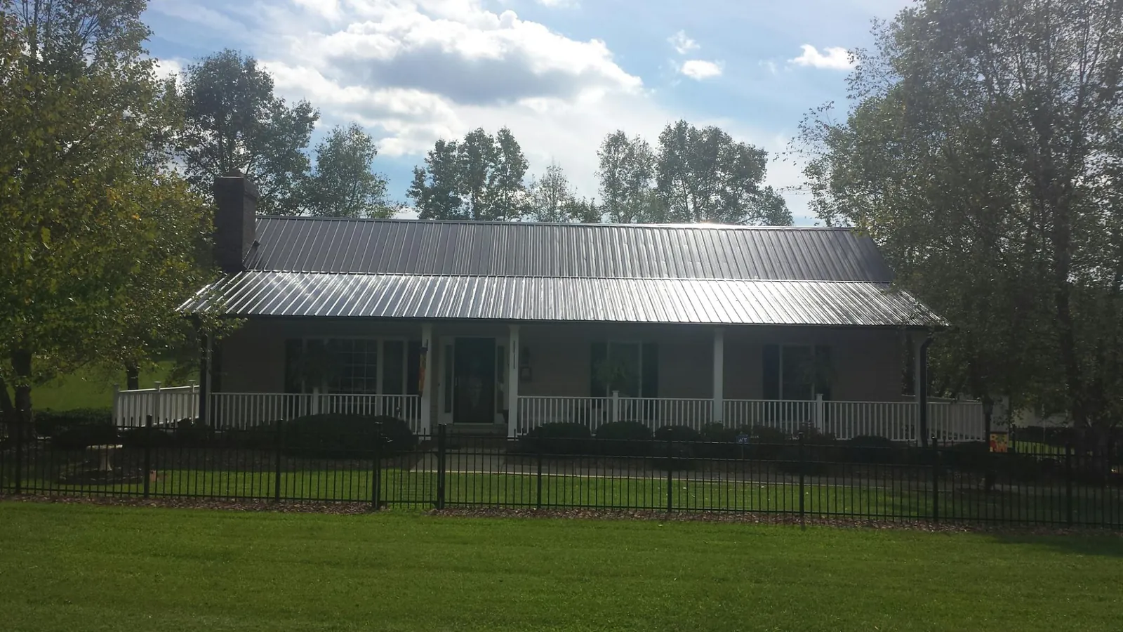 Gray metal roof on a brick ranch with a full width front porch — Gutter Guard Installation work by our crew in Harsens Island