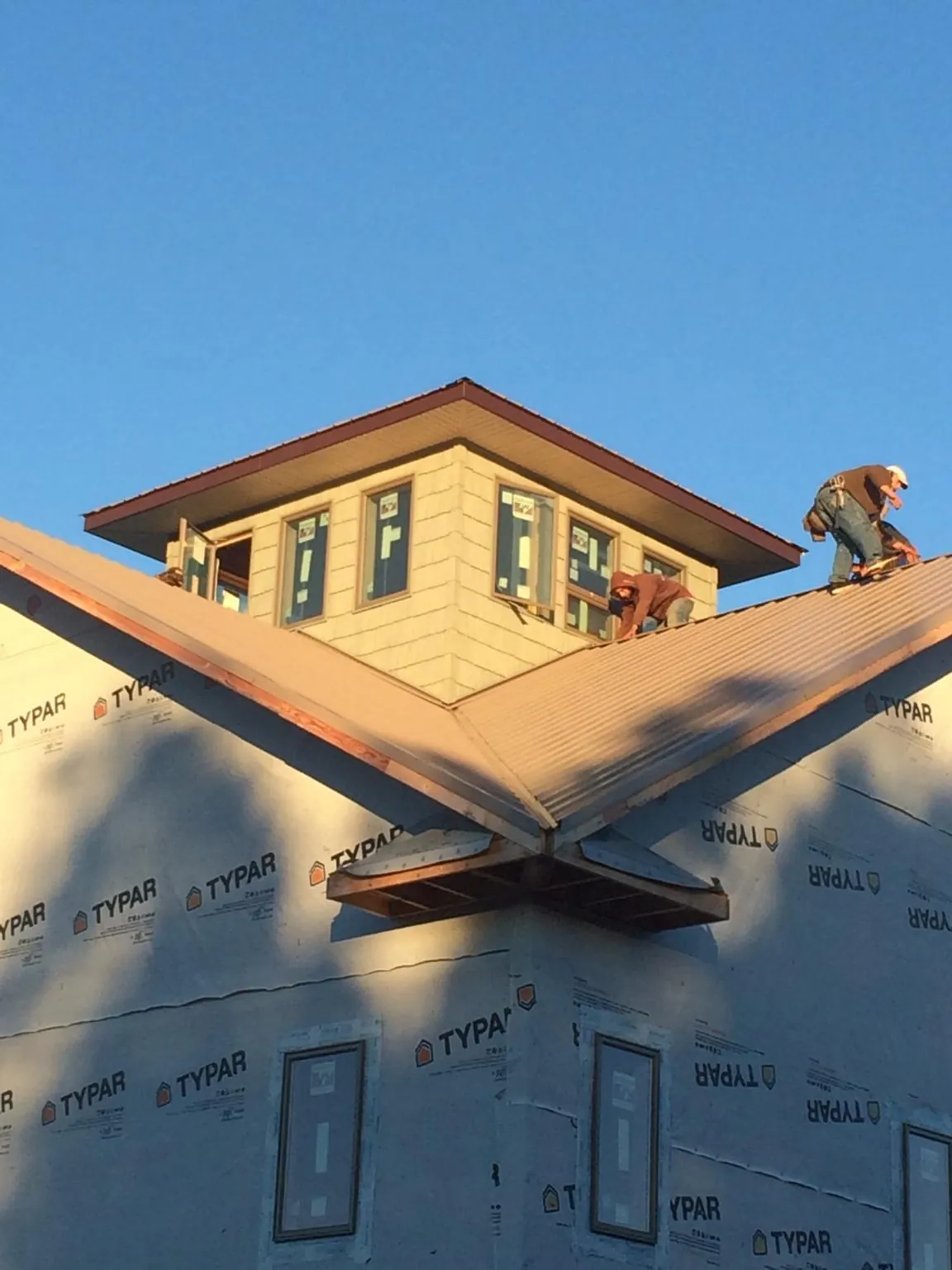 Roofers working around a rooftop cupola on a new metal roof at sunset — Roof Waterproofing in Harsens Island by Roofing Brothers